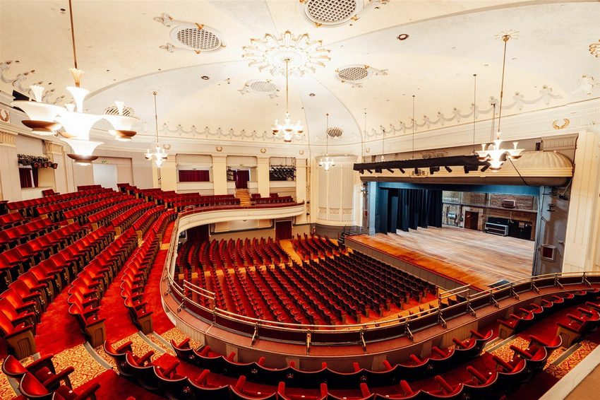 Bournemouth Pavilion's auditorium with rows of differnt levels of curved seating. The red chairs all facing towards the stage over on the rigth of the image.